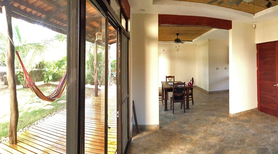 La pièce principale avec accès sur la terrasse en bois, le jardin et la piscine