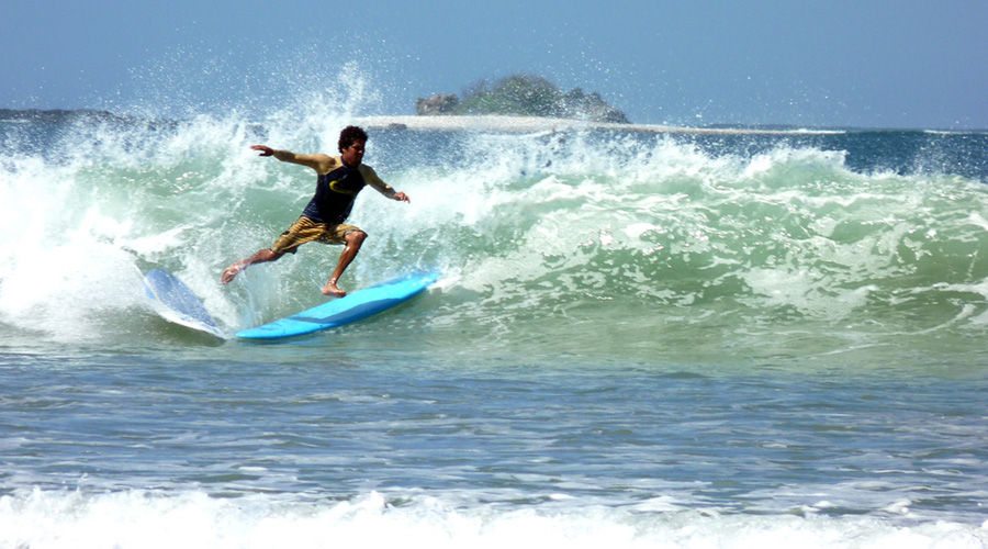 Surfeur sur la plage de Tamarindo. Soit il y a 1 surf de trop, soit il manque un surfeur !